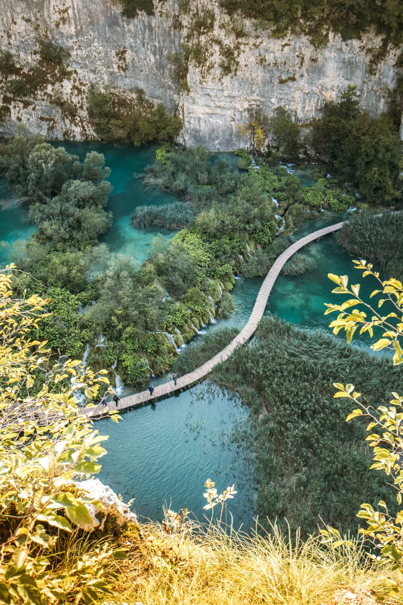 A wooden boardwalk winds over turquoise water at Plitvice